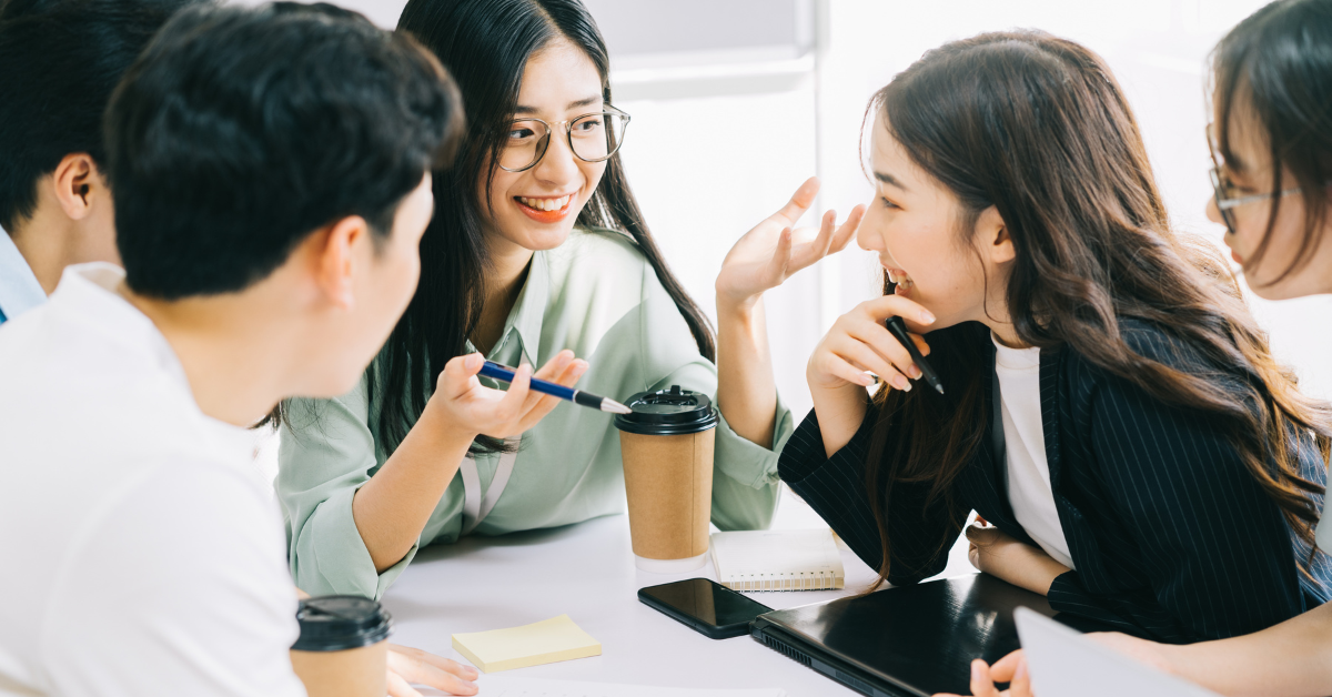 コーヒーを手に持ちながら会話をしているオフィスワーカーたち